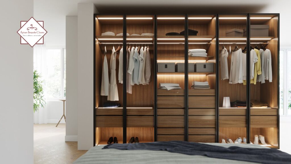 Wooden closet interior with built-in drawers, LED lighting, and clothing hanging neatly inside.